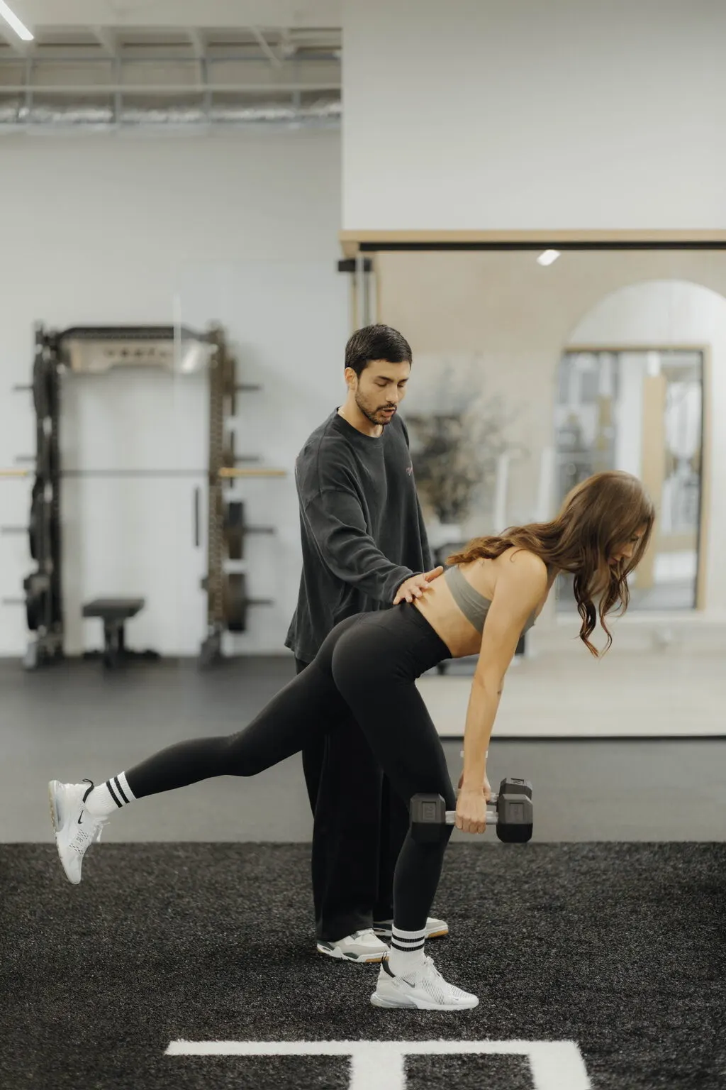 Coach Santi supporting a client's lower back through a single-leg deadlift at Focus Athletics in Costa Mesa, steady coaching that pairs with habit-based nutrition