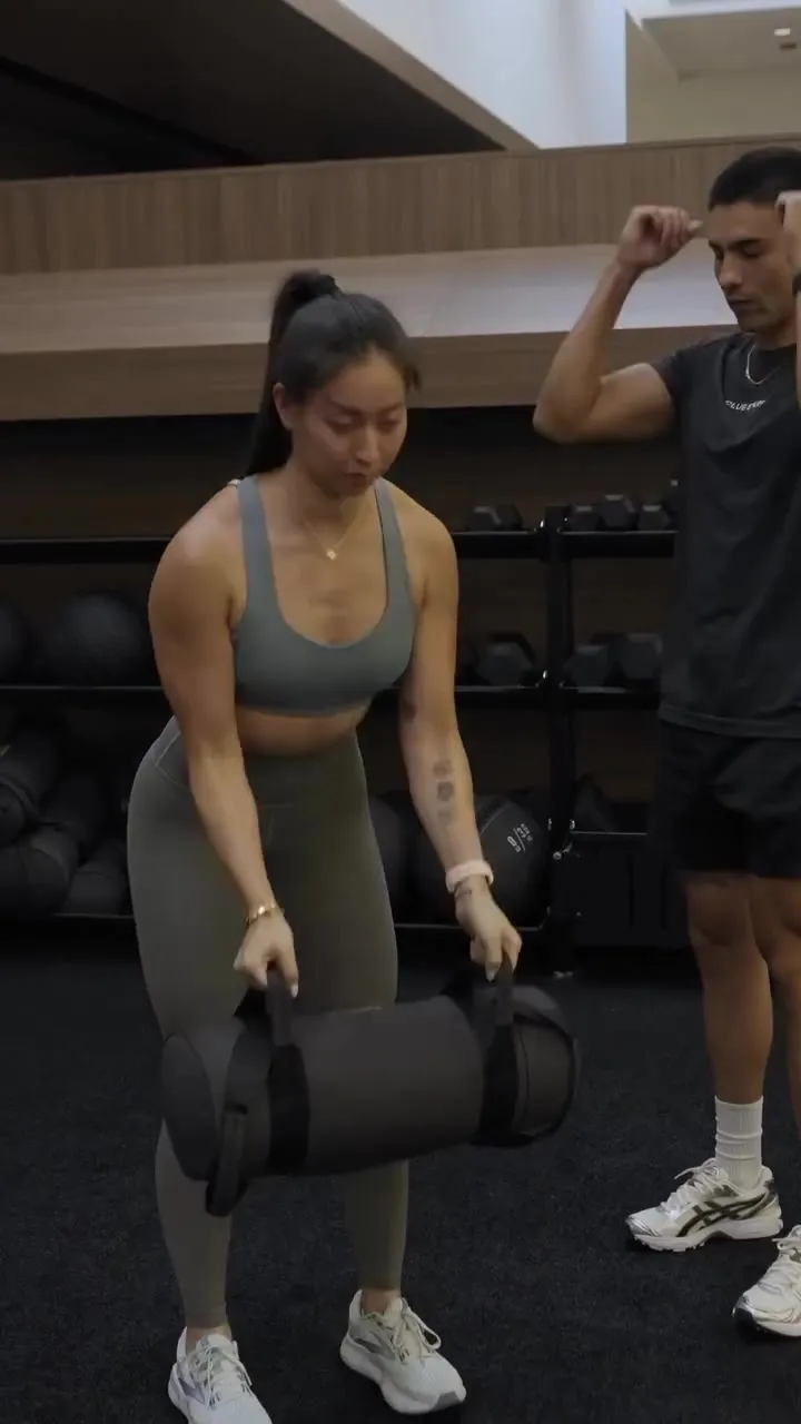 A Costa Mesa client carrying a sandbag as Coach Santi coaches behind, conditioning for sustainable weight loss at Focus Athletics