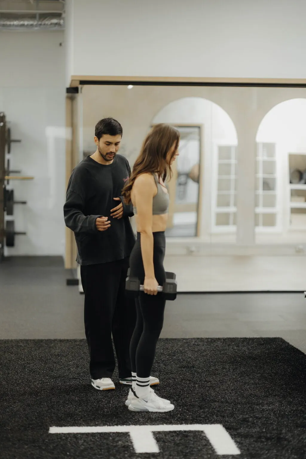 Coach Santi standing beside a client with a dumbbell, cueing the hip hinge at Focus Athletics, where a free consult with a Costa Mesa personal trainer starts