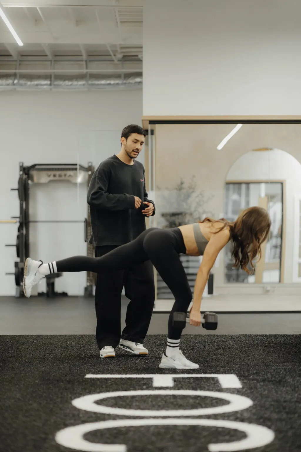 Coach Santi cueing a client through a single-leg dumbbell RDL on the turf at Focus Athletics in Costa Mesa
