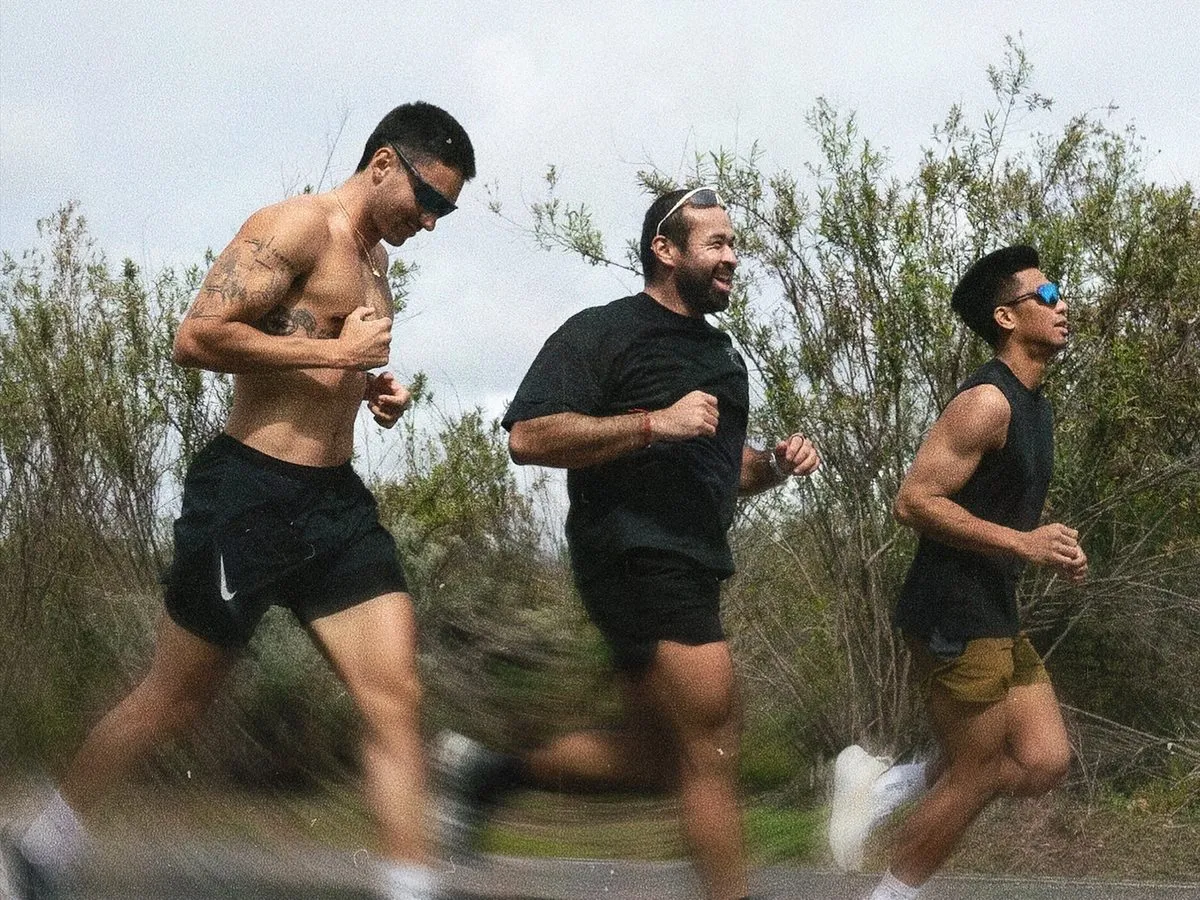Coach Santi running with training partners on an Orange County road, coaching that travels with you